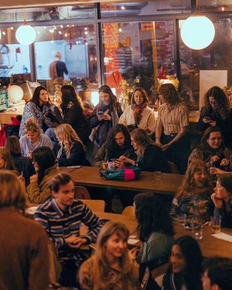 Bezoekers praten en drinken aan de tafels van De Kantine Utrecht